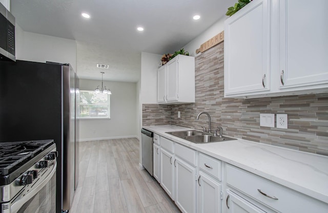 12407 Big Oaks Dr, Houston, TX 77050 - kitchen featuring appliances with stainless steel finishes, light wood finished floors, tasteful backsplash, white cabinetry, and recessed lighting