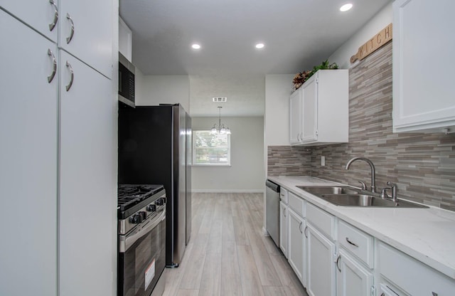 12407 Big Oaks Dr, Houston, TX 77050 - kitchen featuring appliances with stainless steel finishes, white cabinets, backsplash, light wood-style flooring, and recessed lighting