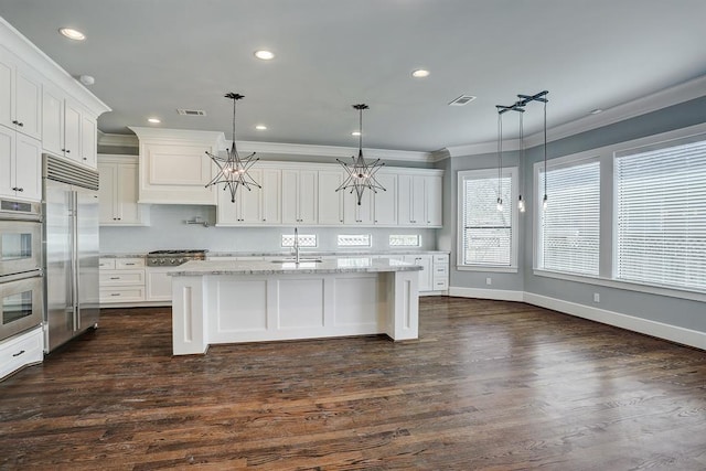 8015 Serenity Ct, Houston, TX 77025 - kitchen featuring appliances with stainless steel finishes, ornamental molding, a chandelier, white cabinets, and light stone countertops