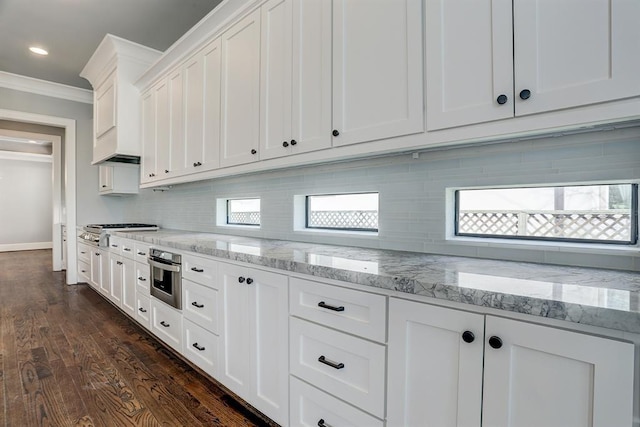 8015 Serenity Ct, Houston, TX 77025 - kitchen with ornamental molding, white cabinetry, stainless steel appliances, tasteful backsplash, and dark wood-type flooring