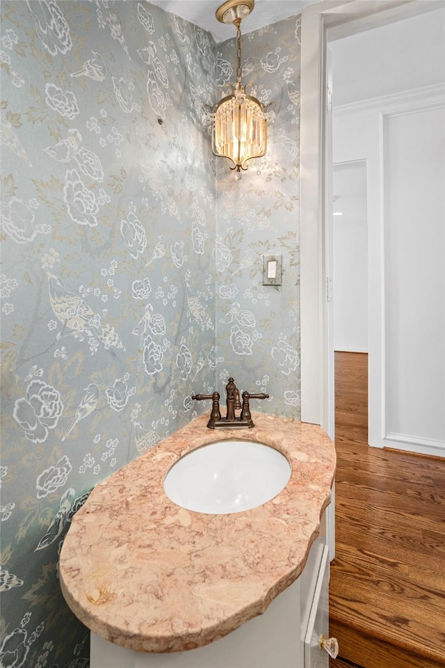 2105 Del Monte Dr, Houston, TX 77019 - bathroom featuring wood finished floors, vanity, a chandelier, and wallpapered walls