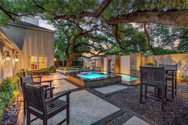 2105 Del Monte Dr, Houston, TX 77019 - patio terrace at dusk with a patio area, an in-ground hot tub, a fenced backyard, and outdoor dining space