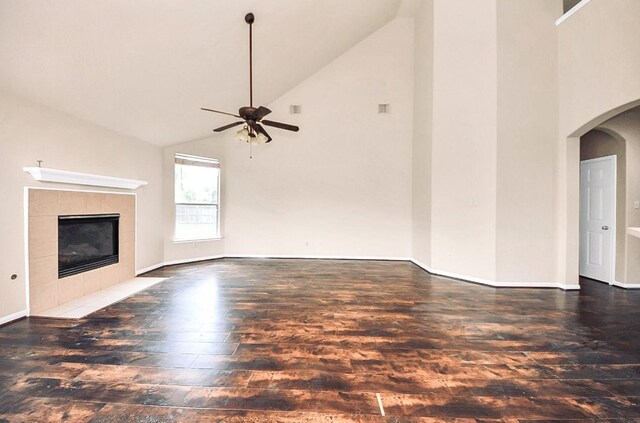 6902 Sterling Meadow Dr, Katy, TX 77449 - unfurnished living room with hardwood / wood-style floors, high vaulted ceiling, ceiling fan, a tiled fireplace, and arched walkways