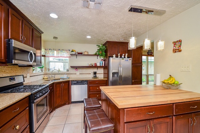 4318 Glen Avon Dr, Pasadena, TX 77505 - kitchen featuring stainless steel appliances, wood counters, a textured ceiling, tasteful backsplash, and hanging light fixtures
