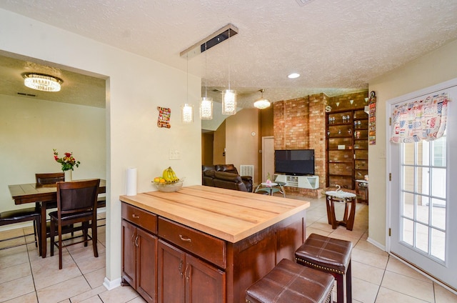 4318 Glen Avon Dr, Pasadena, TX 77505 - kitchen featuring light tile patterned floors, a textured ceiling, wooden counters, pendant lighting, and a kitchen bar