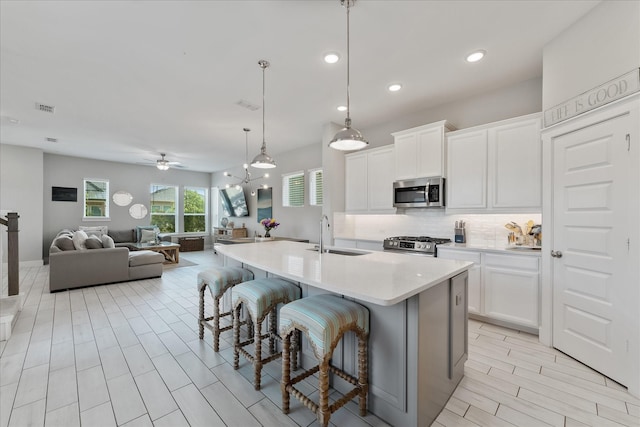 18635 Parkland Square Pl, Cypress, TX 77433 - kitchen featuring appliances with stainless steel finishes, backsplash, a kitchen breakfast bar, light countertops, and white cabinetry
