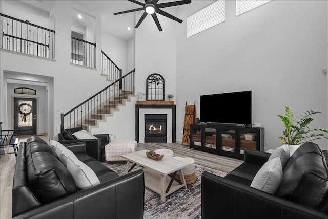 6214 Bois D Arc St, League City, TX 77573 - living area featuring wood finished floors, a high ceiling, a ceiling fan, stairs, and a glass covered fireplace
