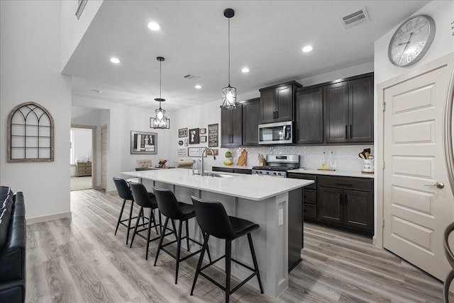 6214 Bois D Arc St, League City, TX 77573 - kitchen featuring appliances with stainless steel finishes, light countertops, a breakfast bar, a center island with sink, and recessed lighting