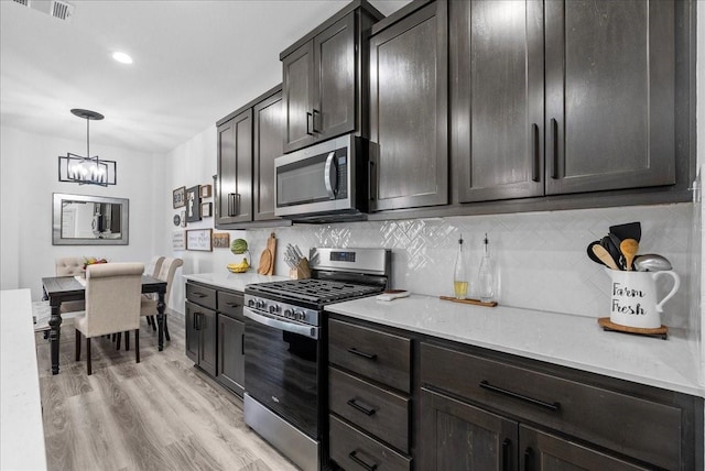 6214 Bois D Arc St, League City, TX 77573 - kitchen with appliances with stainless steel finishes, a chandelier, backsplash, light wood-type flooring, and pendant lighting