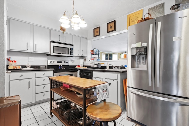 826 Ivyhollow Dr, Channelview, TX 77530 - kitchen with stainless steel appliances, dark countertops, light tile patterned floors, a chandelier, and pendant lighting