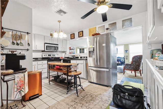 826 Ivyhollow Dr, Channelview, TX 77530 - kitchen featuring stainless steel appliances, dark countertops, ceiling fan, a chandelier, and white cabinetry