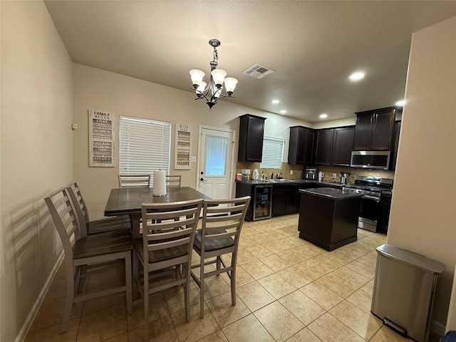 9022 Saint Laurent Ln, Houston, TX 77044 - kitchen featuring stainless steel appliances, a chandelier, a kitchen island, backsplash, and dark cabinets