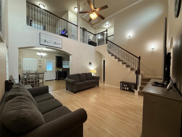 9022 Saint Laurent Ln, Houston, TX 77044 - living room featuring arched walkways, a ceiling fan, light wood-type flooring, a chandelier, and stairway