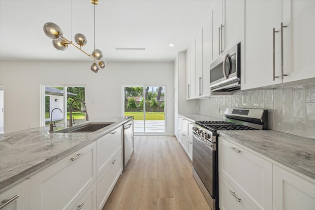 10225 Shadow Oaks Dr, Houston, TX 77043 - kitchen featuring appliances with stainless steel finishes, light wood finished floors, white cabinetry, tasteful backsplash, and light stone counters