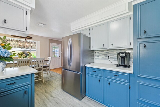 1926 Meadow Creek Dr, Pearland, TX 77581 - kitchen featuring freestanding refrigerator, blue cabinetry, light countertops, light wood-style floors, and decorative backsplash