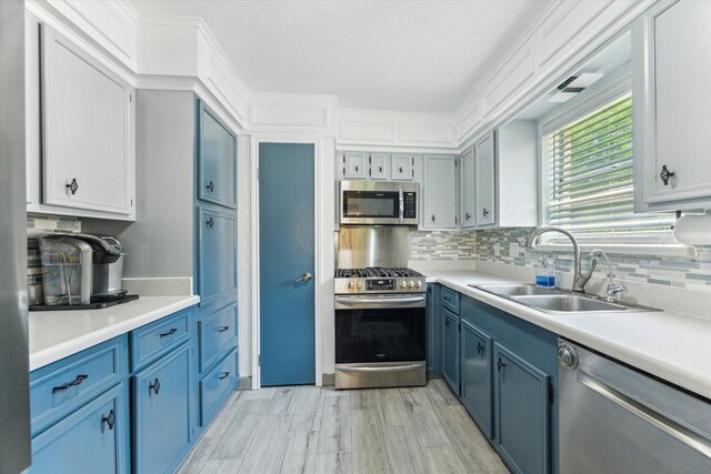 1926 Meadow Creek Dr, Pearland, TX 77581 - kitchen with appliances with stainless steel finishes, blue cabinets, decorative backsplash, light countertops, and light wood-style flooring