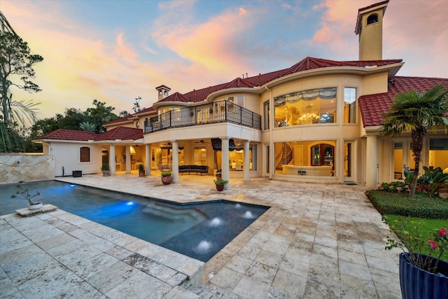 6 Kings Lake Estates Blvd, Kingwood, TX 77346 - back of property at dusk with a balcony, a patio area, a tiled roof, a ceiling fan, and a chimney