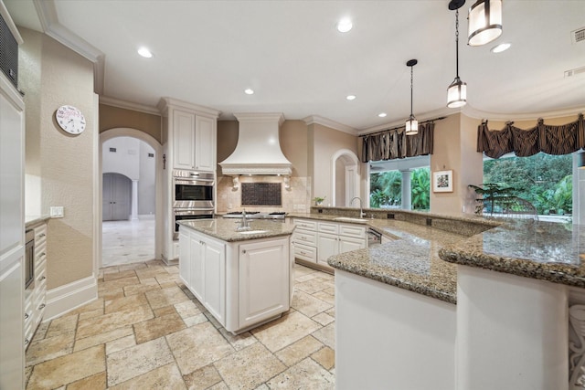 6 Kings Lake Estates Blvd, Kingwood, TX 77346 - kitchen with premium range hood, arched walkways, crown molding, decorative backsplash, and stainless steel appliances