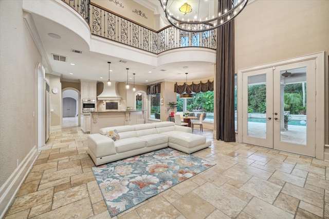 6 Kings Lake Estates Blvd, Kingwood, TX 77346 - living room featuring stone tile floors, crown molding, a chandelier, a towering ceiling, and french doors