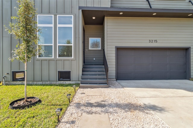 3219 Brewster St, Houston, TX 77026 - view of exterior entry with board and batten siding, an attached garage, a lawn, and driveway