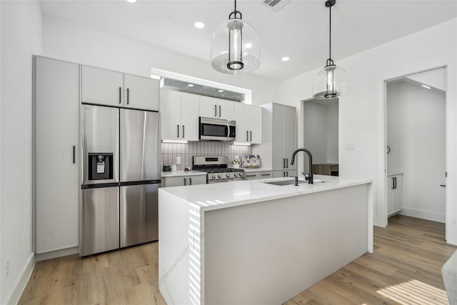 3219 Brewster St, Houston, TX 77026 - kitchen with stainless steel appliances, light countertops, light wood-style floors, backsplash, and decorative light fixtures