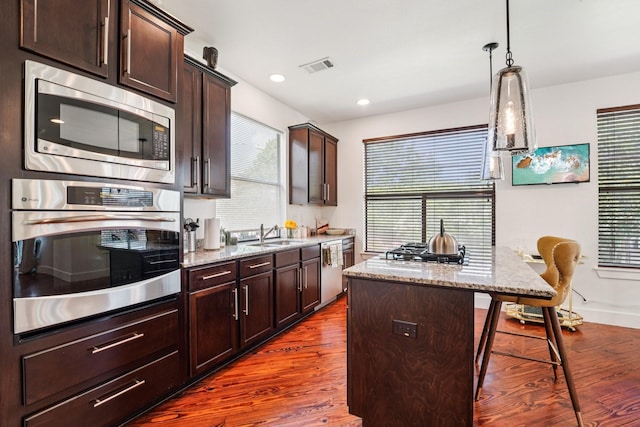 2209 Bastrop St, Houston, TX 77003 - kitchen with stainless steel appliances, light stone counters, dark wood finished floors, dark brown cabinets, and a kitchen island