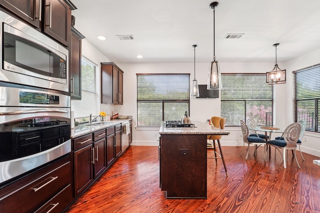 2209 Bastrop St, Houston, TX 77003 - kitchen with stainless steel appliances, a breakfast bar area, light stone countertops, dark brown cabinetry, and recessed lighting