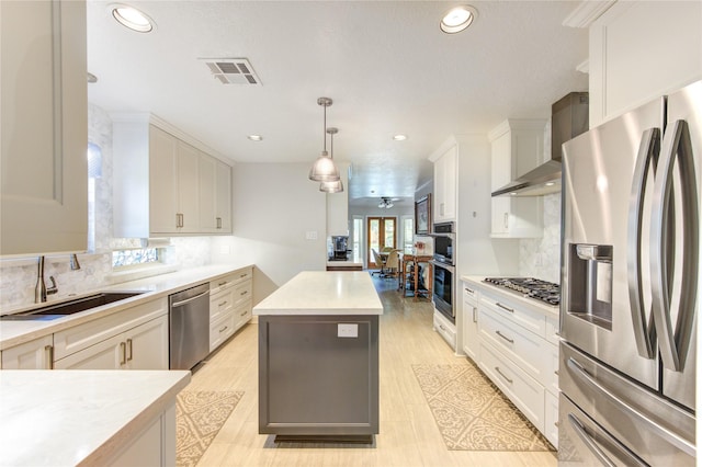 15817 Honolulu St, Jersey Village, TX 77040 - kitchen with stainless steel appliances, wall chimney range hood, a center island, recessed lighting, and white cabinets
