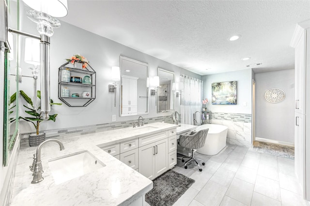 15817 Honolulu St, Jersey Village, TX 77040 - bathroom with tile walls, double vanity, a textured ceiling, recessed lighting, and a freestanding bath