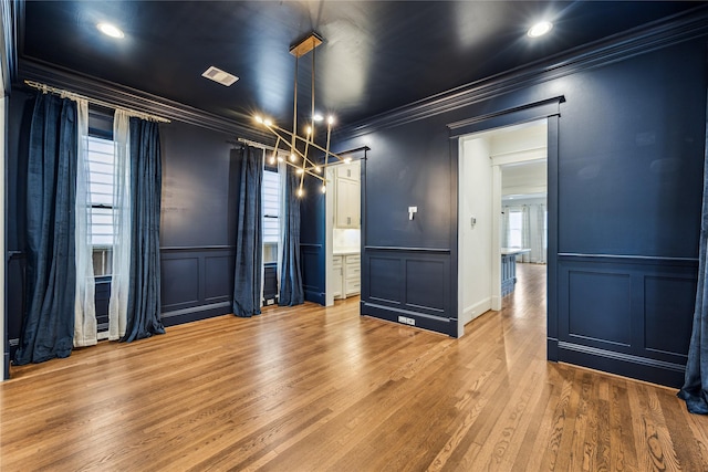 727 Tulane St, Houston, TX 77007 - empty room with a decorative wall, ornamental molding, a chandelier, light wood finished floors, and a wainscoted wall