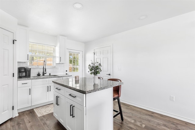 605 Waco St, Dayton, TX 77535 - kitchen with a kitchen breakfast bar, dark wood finished floors, a center island, white cabinets, and dark stone counters