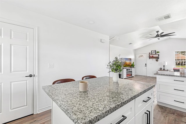 605 Waco St, Dayton, TX 77535 - kitchen featuring wood finished floors, white cabinets, a ceiling fan, and vaulted ceiling