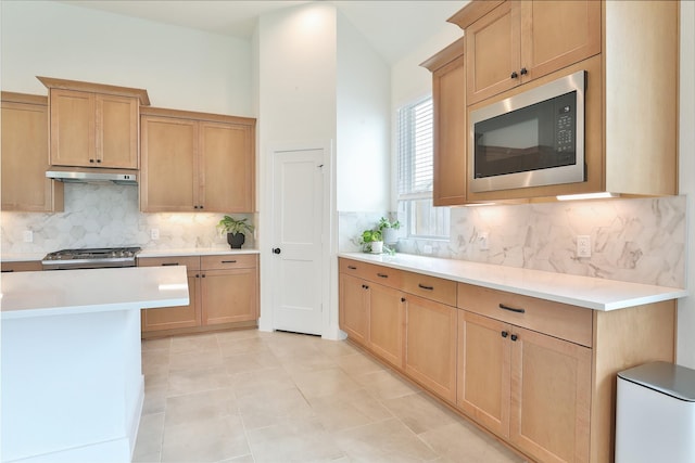 24526 Bluestar Blossom Trl, Katy, TX 77493 - kitchen with built in microwave, backsplash, light countertops, light brown cabinets, and under cabinet range hood