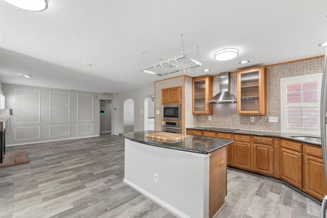 902 Mulberry Ridge Way, Houston, TX 77062 - kitchen featuring wall chimney exhaust hood, stainless steel appliances, a center island, light wood-type flooring, and dark stone counters
