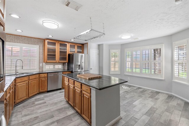 902 Mulberry Ridge Way, Houston, TX 77062 - kitchen with appliances with stainless steel finishes, brown cabinets, a textured ceiling, light wood finished floors, and a kitchen island