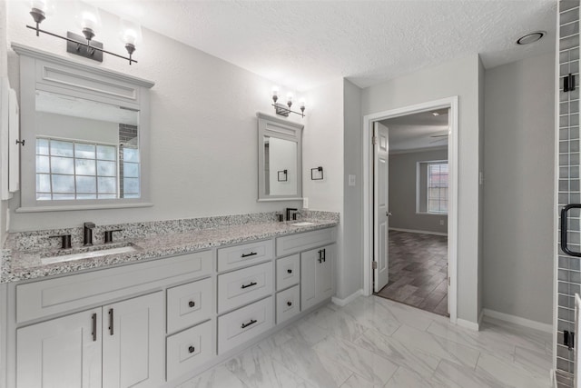 902 Mulberry Ridge Way, Houston, TX 77062 - bathroom featuring double vanity, a textured ceiling, and marble look tiles