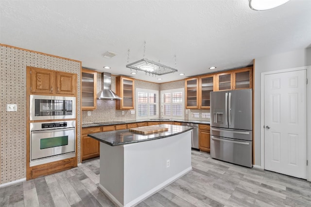 902 Mulberry Ridge Way, Houston, TX 77062 - kitchen featuring stainless steel appliances, wall chimney range hood, light wood-type flooring, brown cabinetry, and recessed lighting