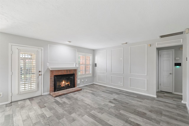 902 Mulberry Ridge Way, Houston, TX 77062 - unfurnished living room with a brick fireplace, wood finished floors, and a textured ceiling