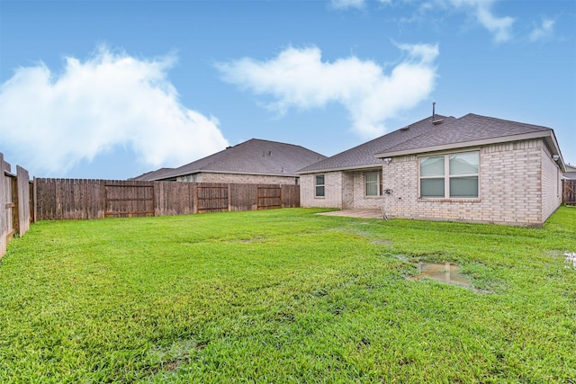19911 Paros Island Dr, Hockley, TX 77447 - back of property with a fenced backyard, roof with shingles, brick siding, and a patio area