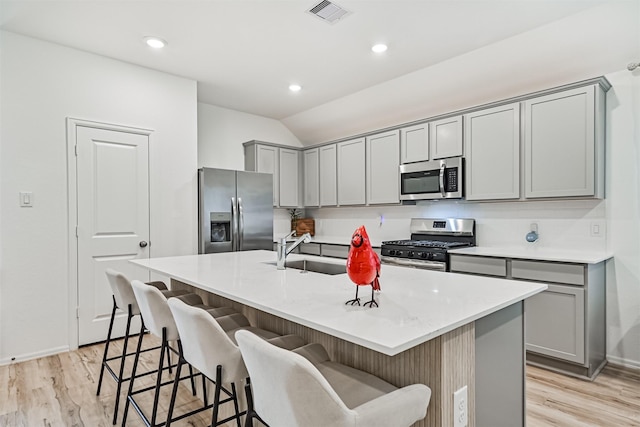 19911 Paros Island Dr, Hockley, TX 77447 - kitchen featuring appliances with stainless steel finishes, gray cabinets, light wood-type flooring, a kitchen breakfast bar, and lofted ceiling