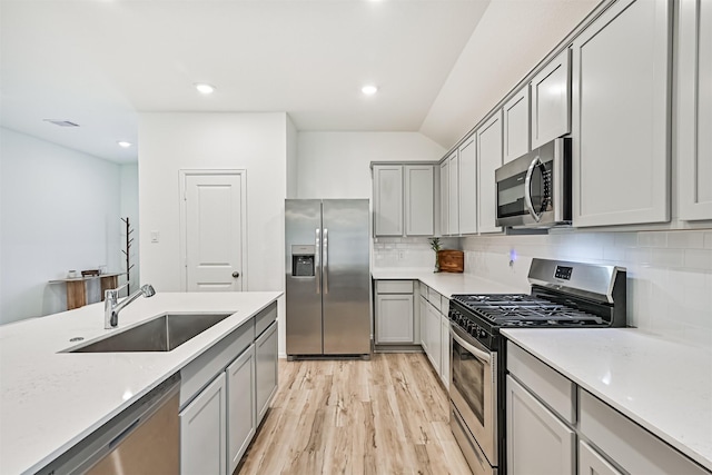 19911 Paros Island Dr, Hockley, TX 77447 - kitchen featuring appliances with stainless steel finishes, gray cabinetry, tasteful backsplash, light wood-style floors, and light countertops