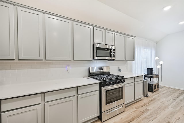 19911 Paros Island Dr, Hockley, TX 77447 - kitchen with appliances with stainless steel finishes, gray cabinetry, decorative backsplash, vaulted ceiling, and recessed lighting