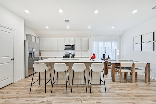 19911 Paros Island Dr, Hockley, TX 77447 - kitchen with stainless steel appliances, light countertops, light wood-style floors, an island with sink, and a kitchen breakfast bar