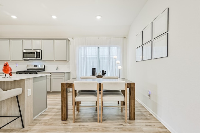19911 Paros Island Dr, Hockley, TX 77447 - kitchen featuring stainless steel appliances, light wood-type flooring, a kitchen breakfast bar, light countertops, and gray cabinetry