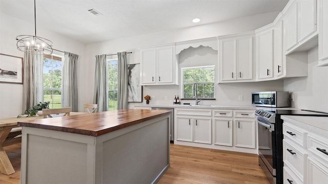 27938 Deer Run St, Montgomery, TX 77356 - kitchen featuring appliances with stainless steel finishes, butcher block counters, white cabinetry, light wood-style flooring, and a chandelier