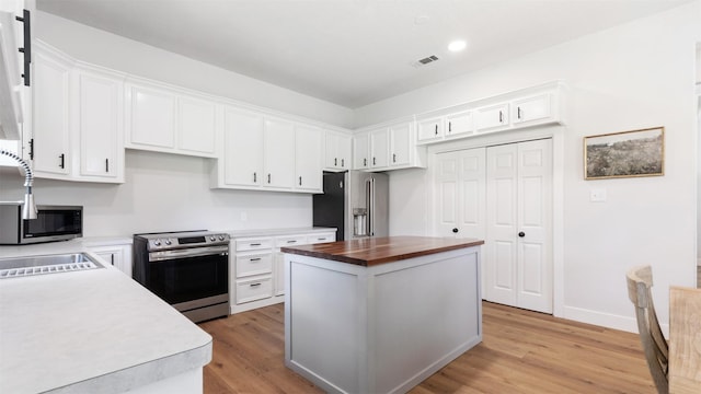 27938 Deer Run St, Montgomery, TX 77356 - kitchen with stainless steel appliances, butcher block countertops, light wood-style floors, white cabinets, and recessed lighting