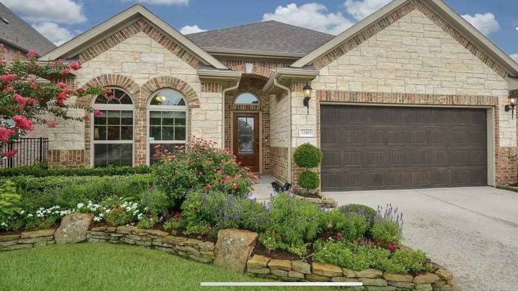 23415 Farfalla Ln, Richmond, TX 77406 - french provincial home with stone siding, an attached garage, and driveway