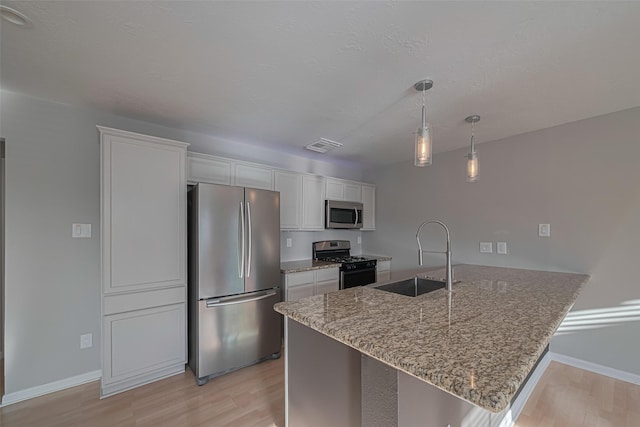 1101 Saulnier St, Houston, TX 77019 - kitchen featuring appliances with stainless steel finishes, white cabinetry, a peninsula, and light wood-style floors