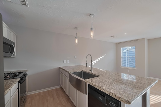 1101 Saulnier St, Houston, TX 77019 - kitchen featuring stainless steel appliances, a peninsula, light wood finished floors, light stone countertops, and white cabinets