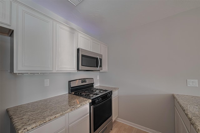 1101 Saulnier St, Houston, TX 77019 - kitchen with appliances with stainless steel finishes, light wood finished floors, white cabinets, and light stone counters